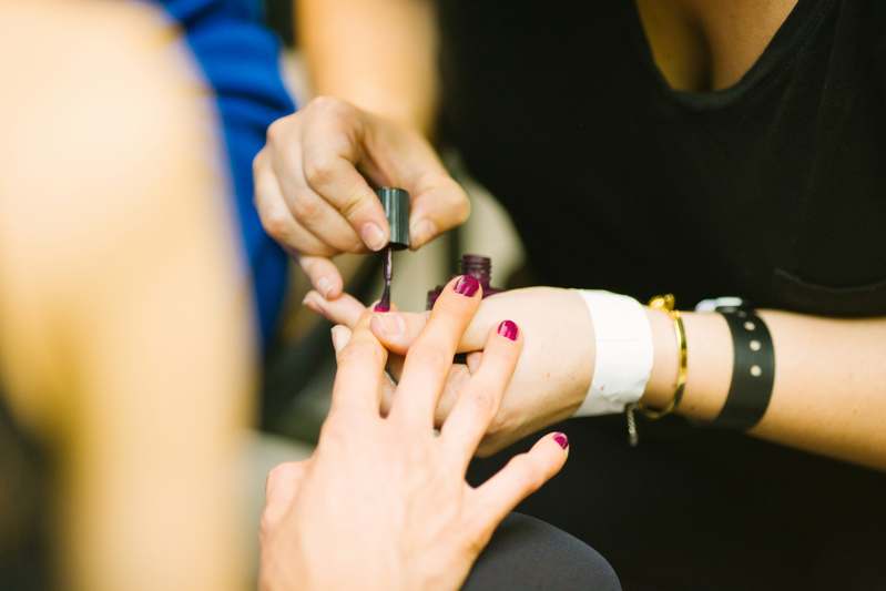 Hands applying clear nail strengthener with brush applicator